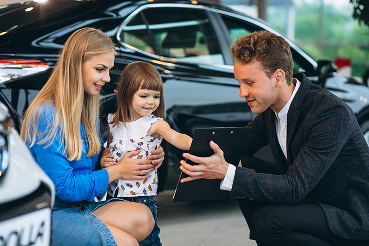 Mother with daughter talking to sales person in a car showroom Mother with daughter talking to sales person in a car showroom